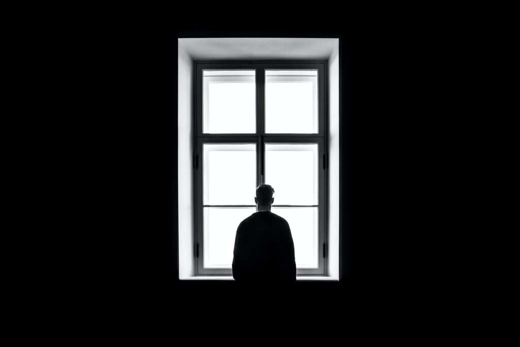 man standing alone at a window. how to build trust when you have trust issues