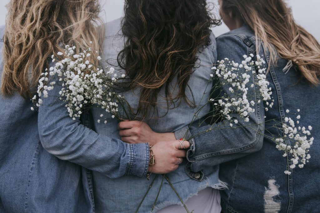 group of women with their back towards us, holding flowers and arms around each other